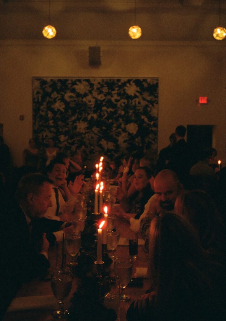 35mm film photo of guests talking and eating to candlelight at a long table