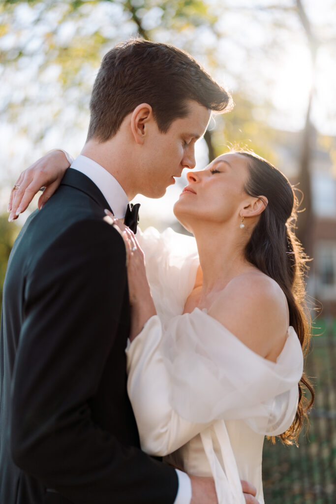 beautiful backlit with natural golden hour sunlight photo of a bride falling into her groom's embrace