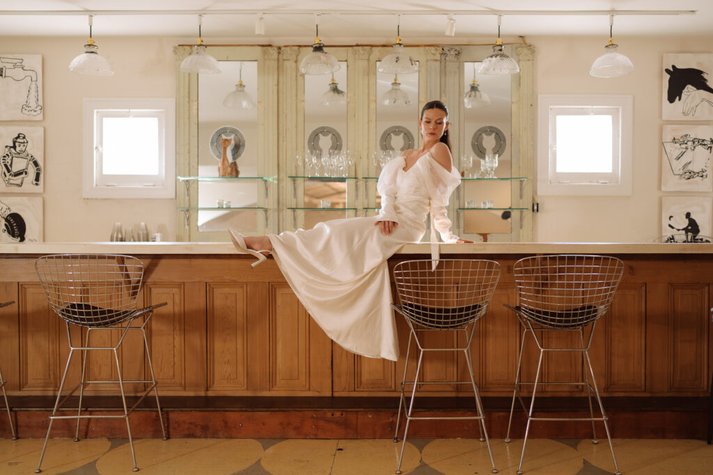 stylish bride sitting on a retro wooden bar with mirrors in the background