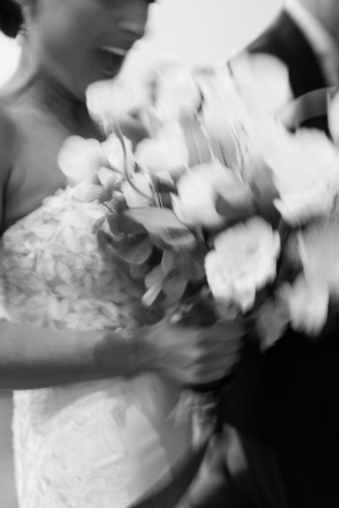 Close-up motion blur of bride holding bouquet during joyful wedding celebration at The Marquee at New Town