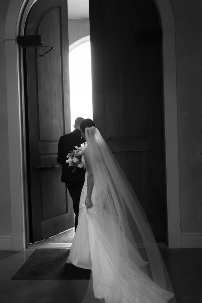 Bride and groom walking out large wooden church doors after wedding ceremony at The Marquee at New Town