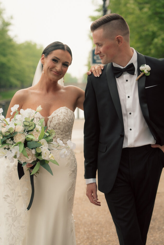 Bride smiling with hand on groom’s shoulder during wedding portraits at The Marquee at New Town