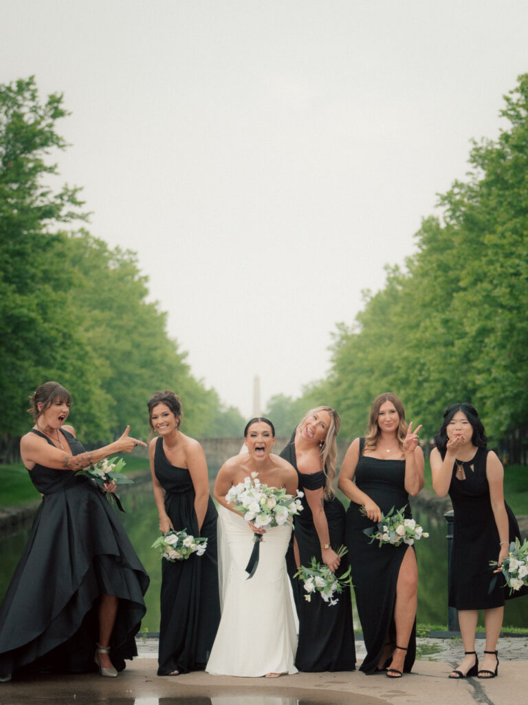 Bride laughing with bridesmaids in black dresses during wedding party portraits at The Marquee at New Town
