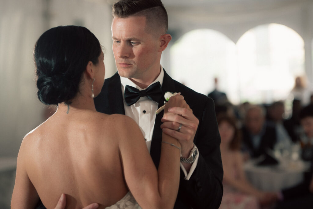 Groom looking at bride during first dance under tented reception at The Marquee at New Town