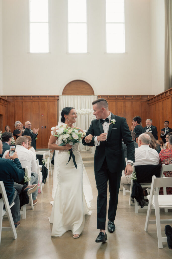 Bride and groom walking up the aisle smiling after wedding ceremony at The Marquee at New Town