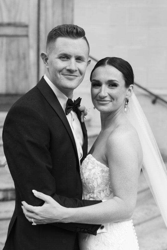 Bride and groom embracing in front of stone steps after wedding ceremony at The Marquee at New Town