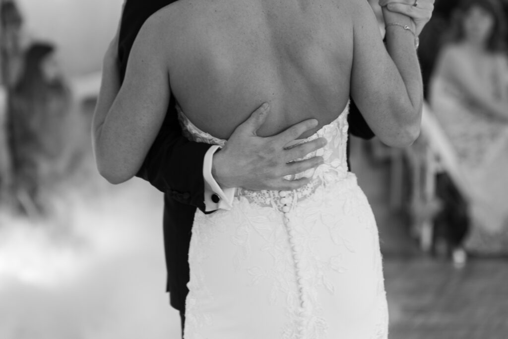 Close-up of groom’s hand on bride’s back during emotional first dance at The Marquee at New Town