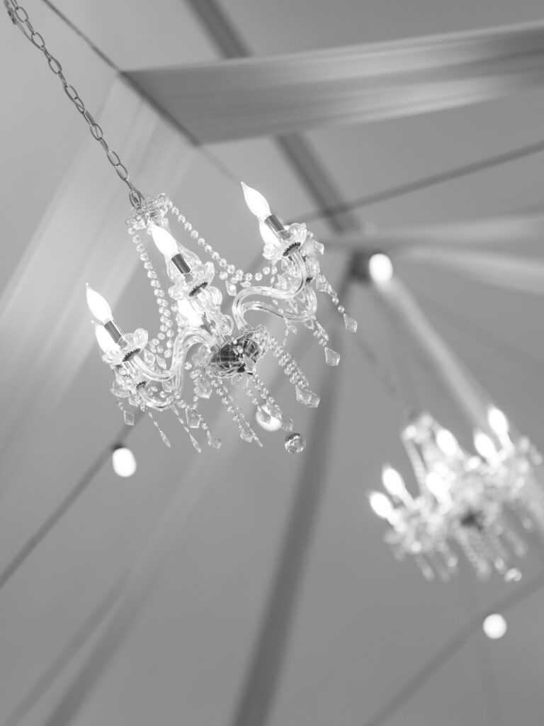 Crystal chandeliers hanging inside white wedding tent with drapery at The Marquee at New Town